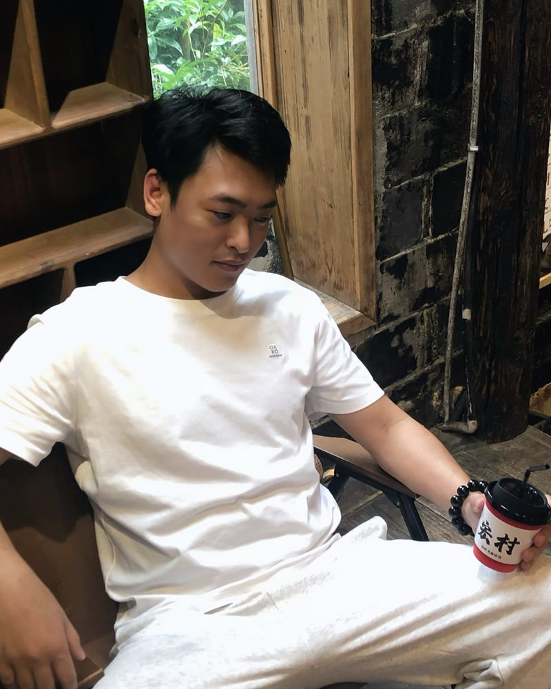 朱明君坐在木屋里,手里拿着一杯咖啡